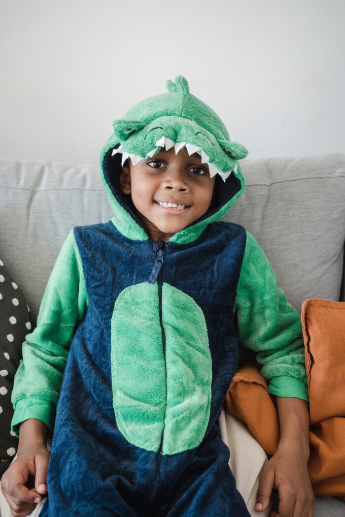 Child wearing a dinosaur onesie, part of our sustainable dinosaur clothes collection."