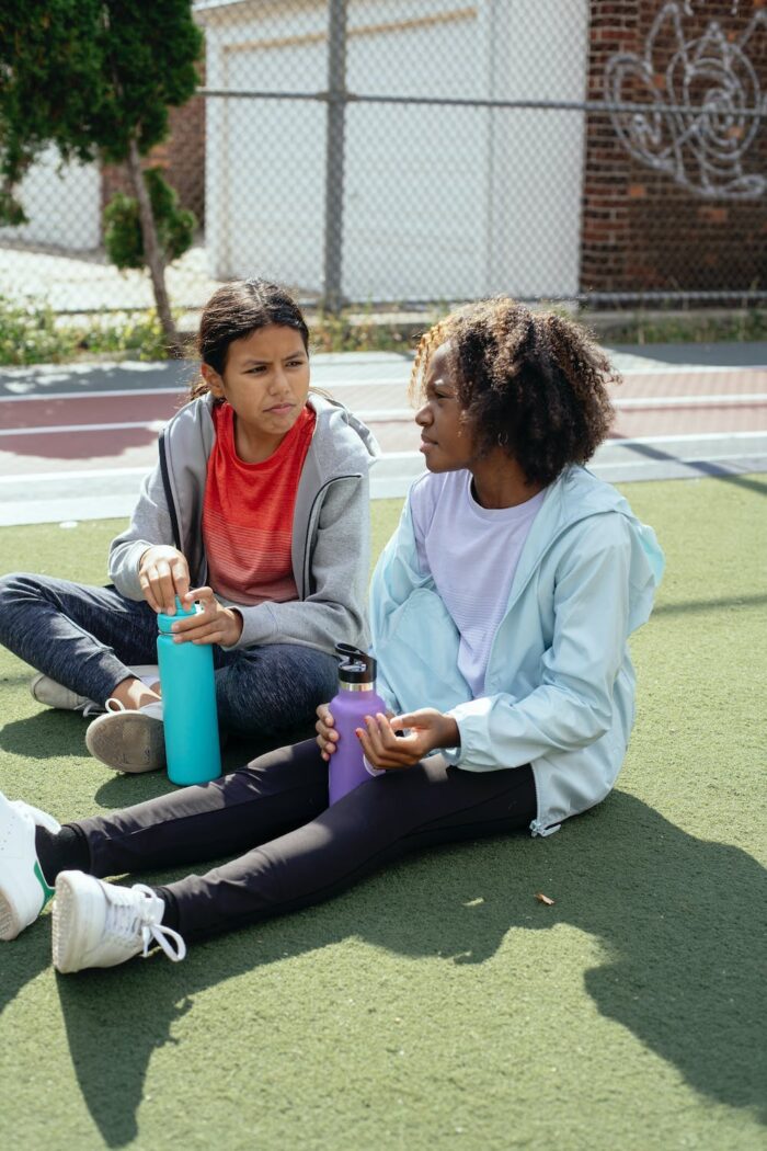 Two girls hydrating after sports, wearing sustainable sporty clothes